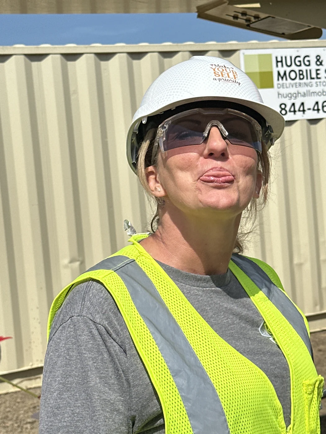 Amy at work wearing a hard hat, safety glasses, and reflective vest